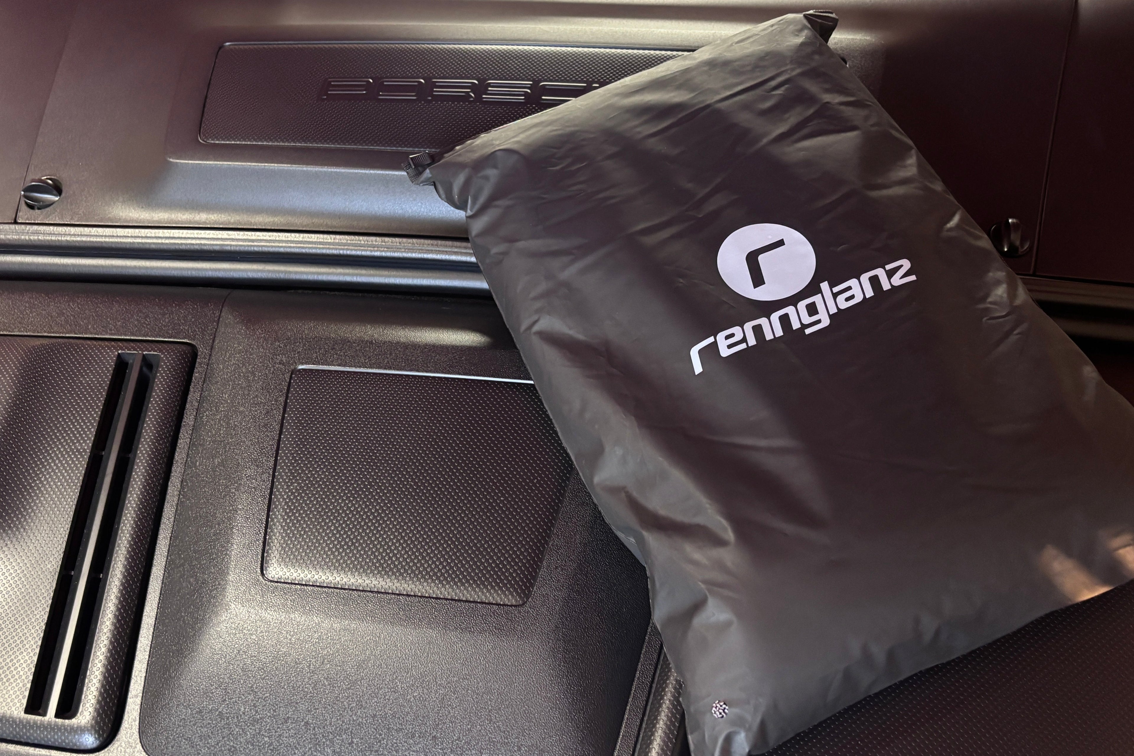 Black bag with a logo on a car's open glove compartment.